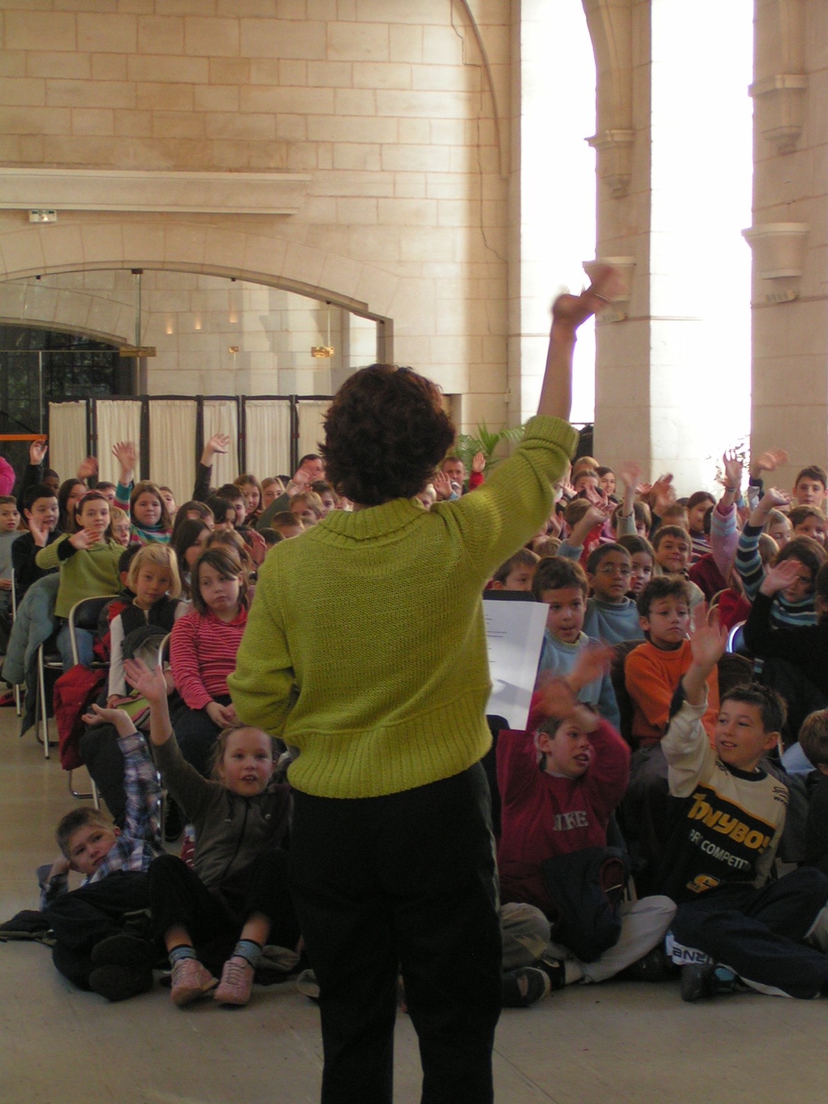 Petra vor einem Saal voller Kinder, die sich melden